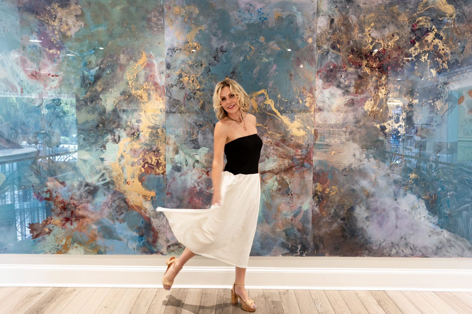 Summer Savin in front of a large blue-and-gold LUCiTE reverse-acrylic mural
