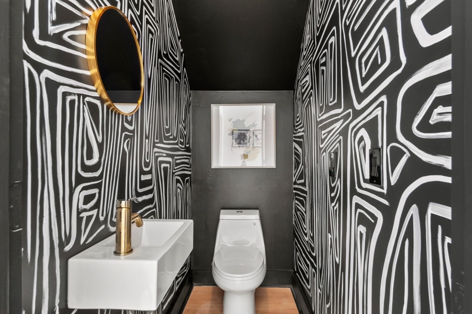 Bold black-and-white LUCiTE powder room with a brass mirror