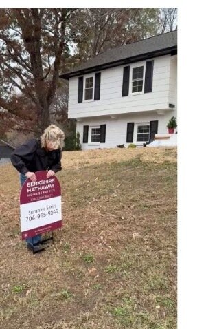 Summer Savin placing a Berkshire Hathaway HomeServices sign in the yard of a listed home